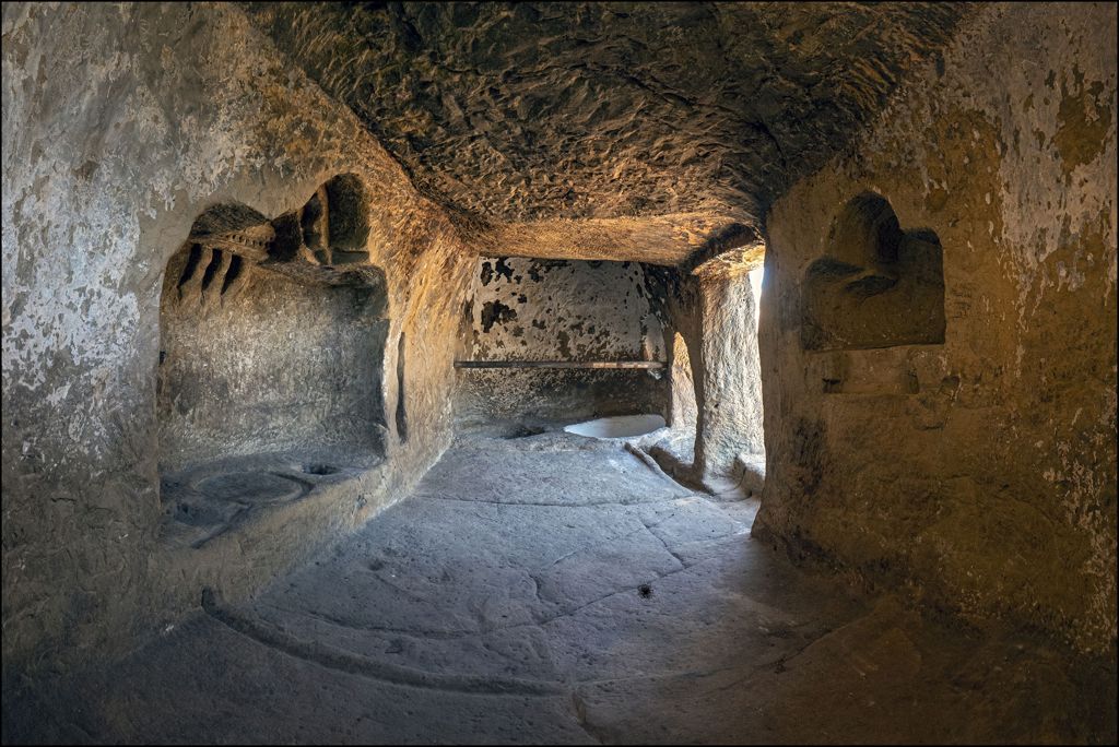Detalle interior de la Casa de Piedra de Cortes de la Frontera mostrando tinajas excavadas en el suelo y el hueco de la prensa del lagar de los siglos XVIII y XIX